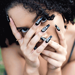 hands in front of face showing custom black press on nails with white gothic lettering